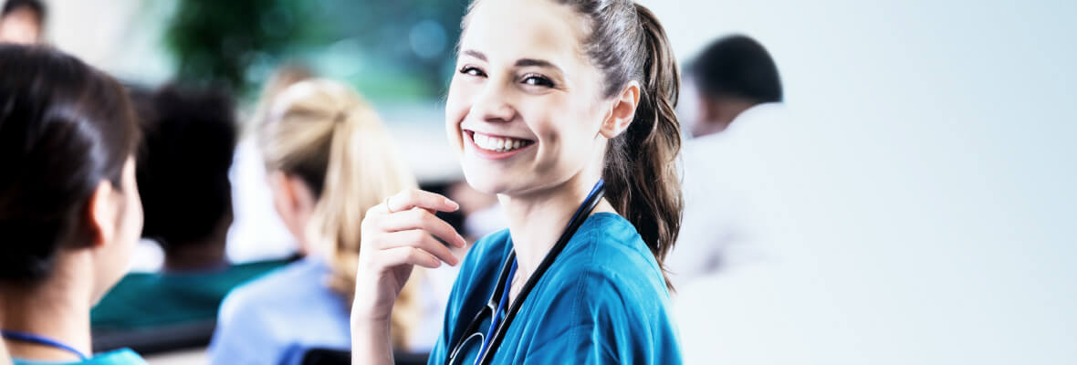 eine junge Krankenpflegehelferin lächelt in die Kamera.