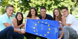 Rine Gruppe junger Menschen schwenkt eine Europa-Flagge.