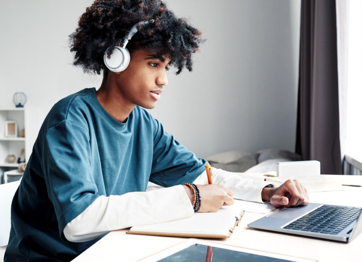 Schüler sitzt mit Kopfhörern vor Laptop