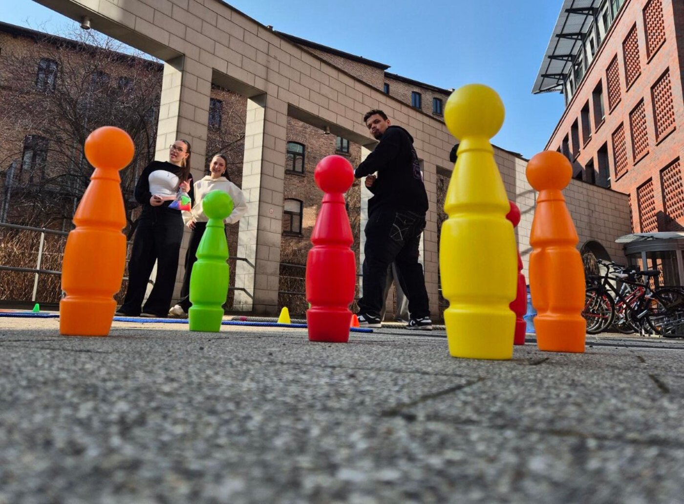 Auszubildende nehmen an den WBS SCHULEN Halle an einem Bewegungsspiel im Freien teil. Zwischen farbigen Spielfiguren fördern Teamaufgaben, Koordination und gemeinsames Lernen den Zusammenhalt der Gruppe.