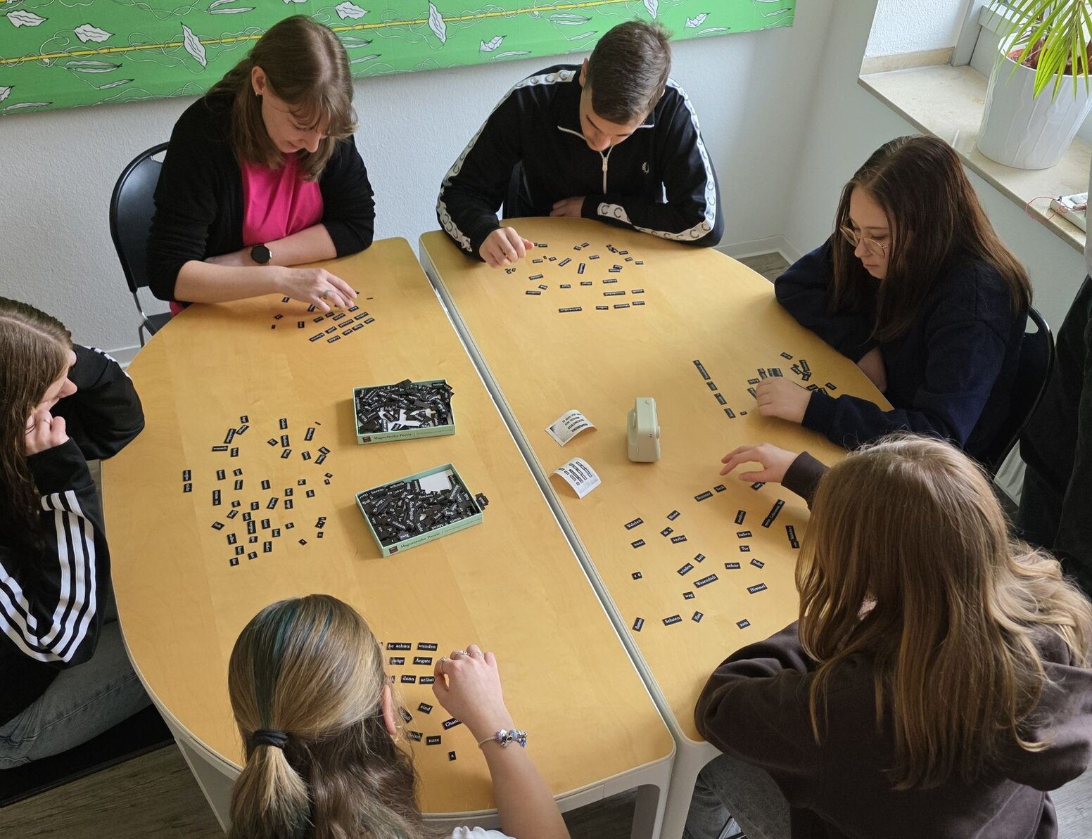 Sechs Schüler:innen bearbeiten an einem Tisch eine Aufgabe mit vielen Wortkärtchen.
