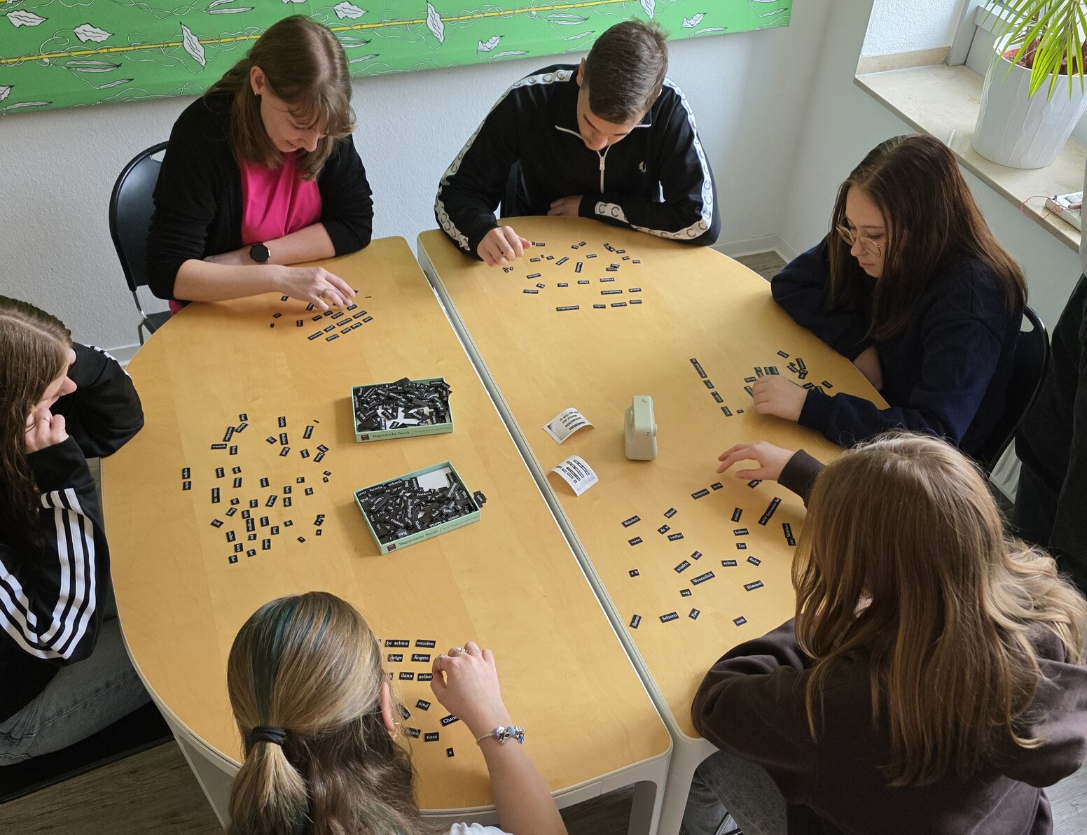 Sechs Schüler:innen bearbeiten an einem Tisch eine Aufgabe mit vielen Wortkärtchen.