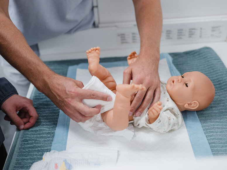 Auszubildende üben handlungsorientiert das Wickeln an einer Babypuppe im SkillsLab für die Pflegeausbildung.