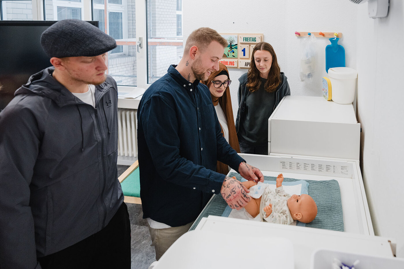 Ein Pflegepädagoge erklärt den Auszubildenden die Pflege am Säugling