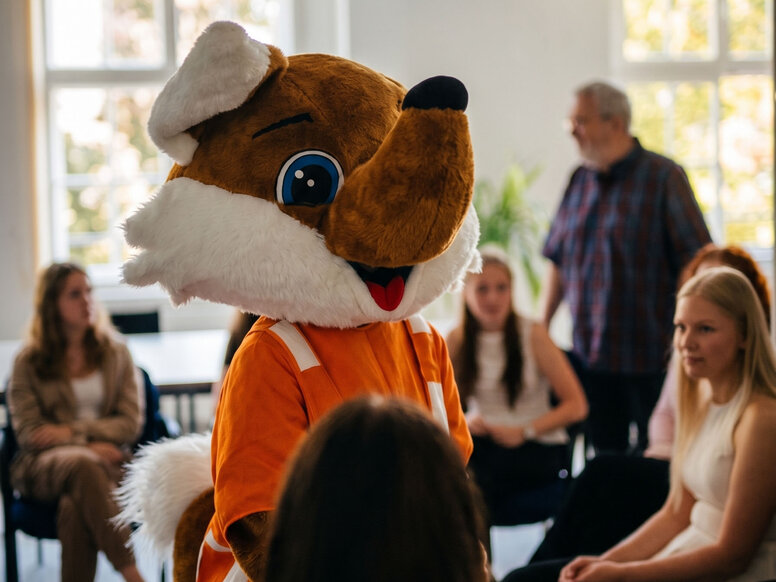 Schlaufuchs begrüßt neue Auszubildende zum Schulbeginn in Chemnitz. Die Figur steht im Mittelpunkt eines Stuhlkreises und unterstützt eine freundliche Atmosphäre zum Ausbildungsstart.