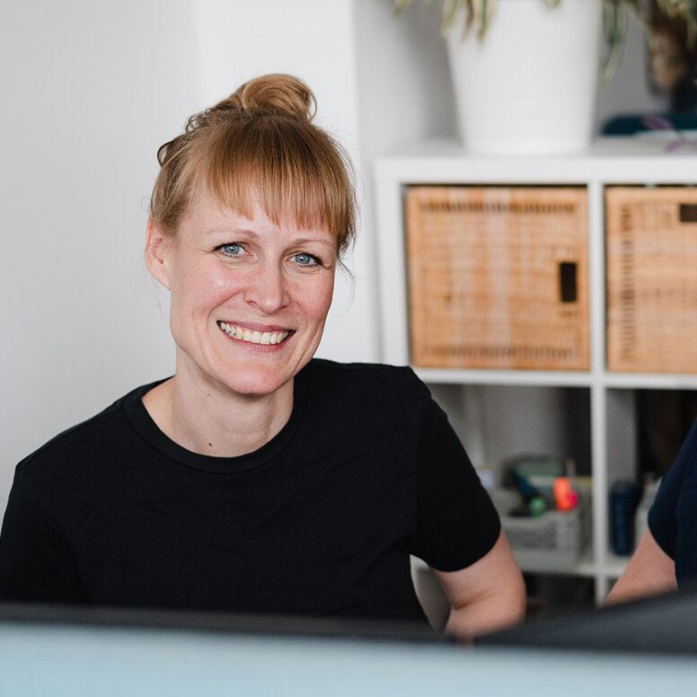 Zwei Mitarbeiterinnen der WBS SCHULEN sitzen nebeneinander vor ihrem Bildschirmen und arbeiten an einem gemeinsamen Projekt. 