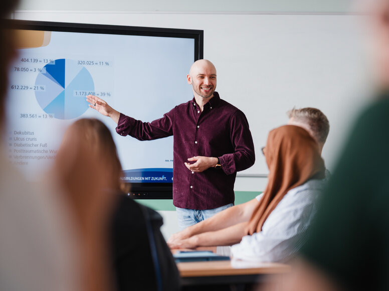 Dozent hält eine praxisorientierte Präsentation über Ausbildungsberufe im modernen Klassenzimmer mit interaktivem Bildschirm.