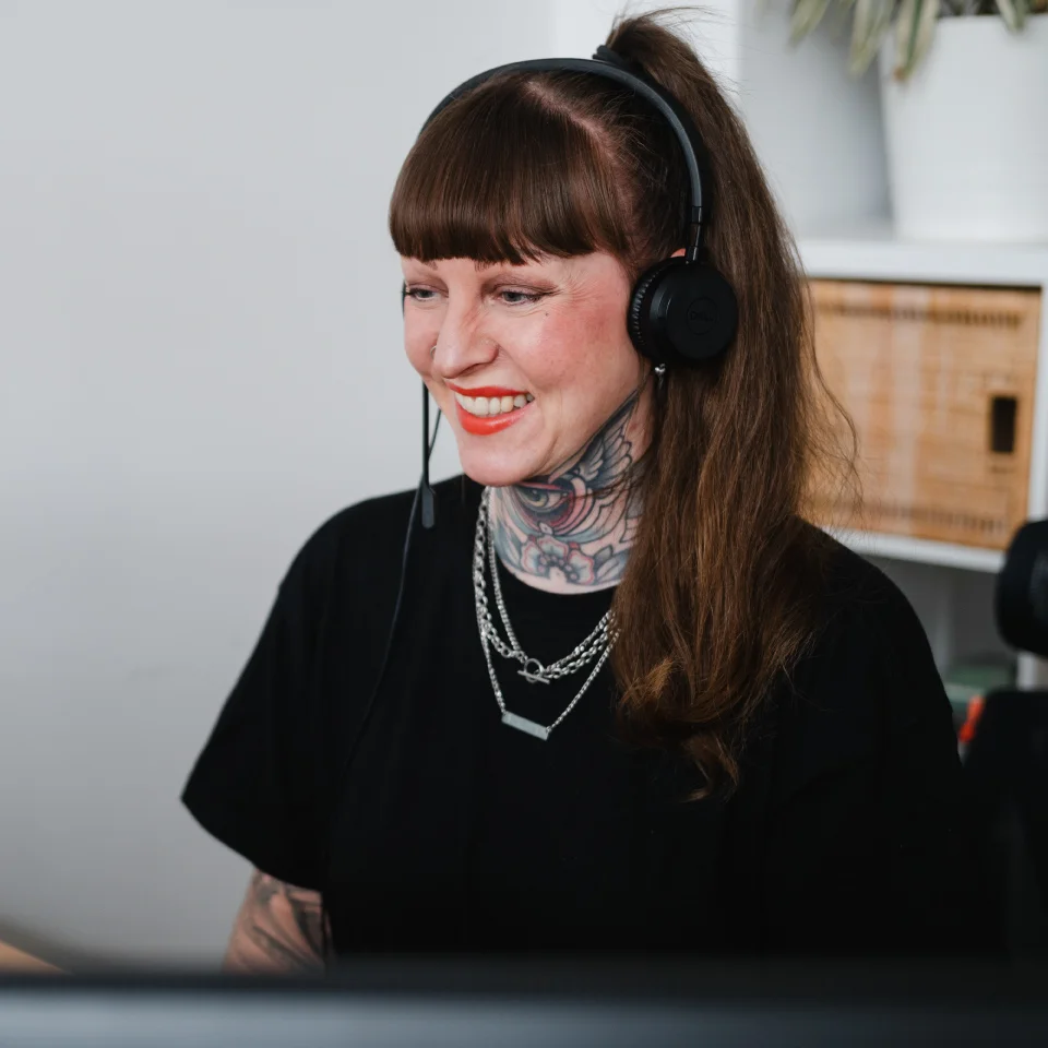 Eine Beraterin mit Headset sitzt an einem Arbeitsplatz vor einem Bildschirm in einem Büro.