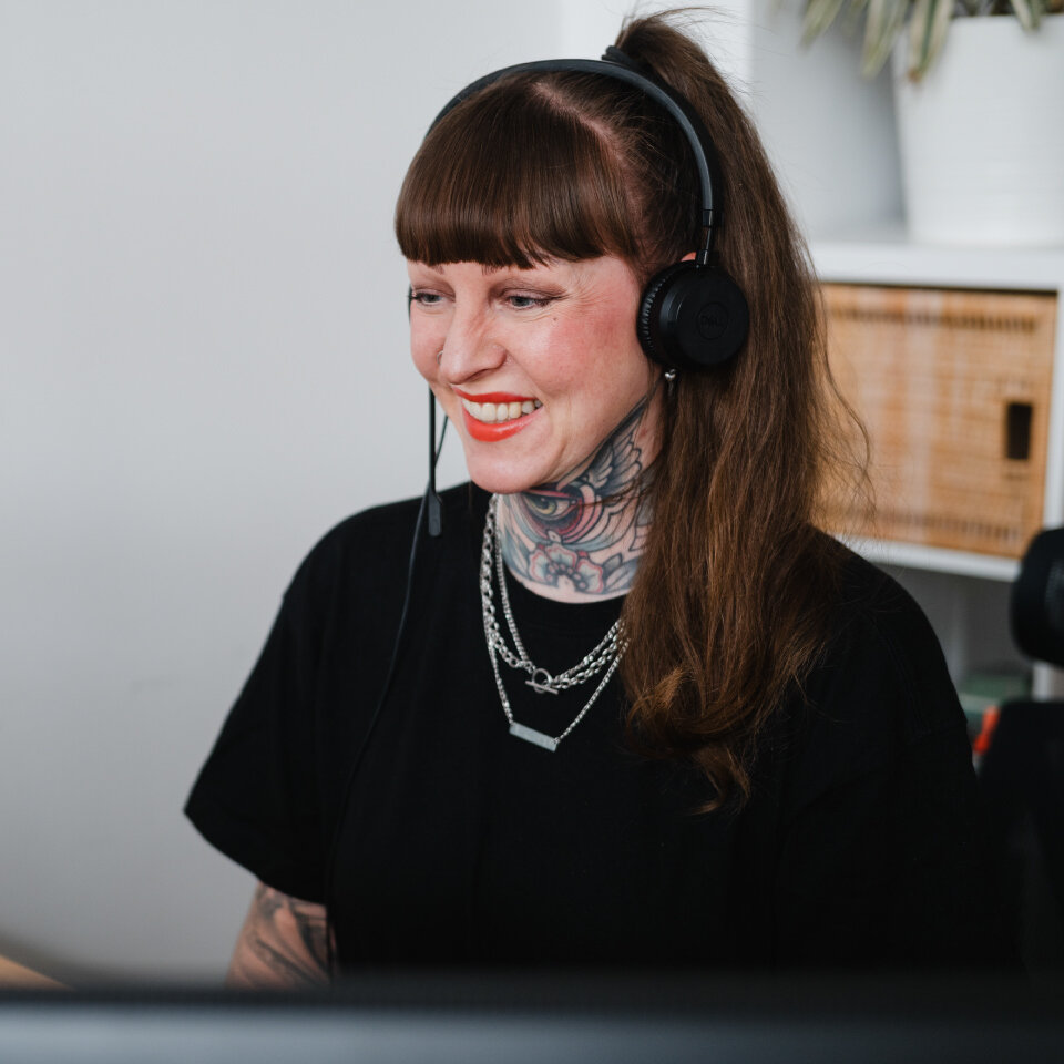 Eine Beraterin mit Headset sitzt an einem Arbeitsplatz vor einem Bildschirm in einem Büro.