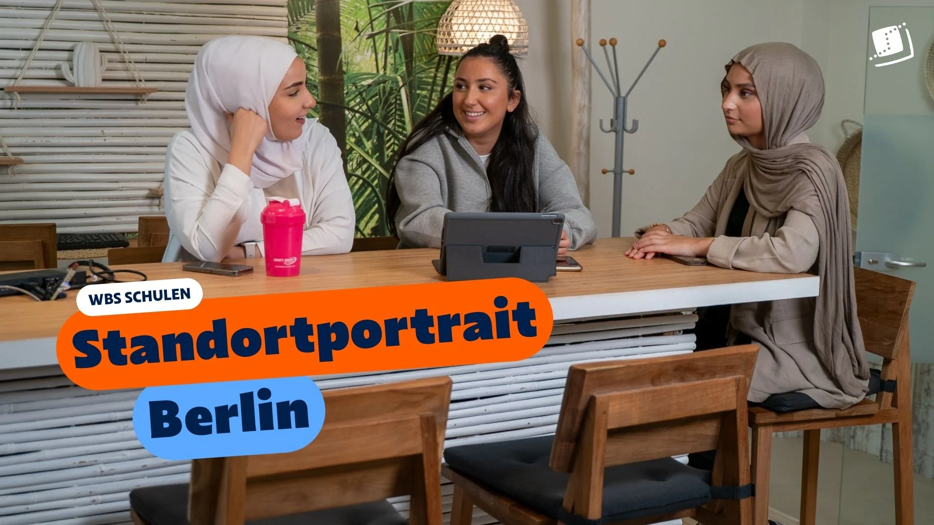 Drei multikulturelle Schülerinnen sitzen an einem Holztisch in einem modern eingerichteten Schulungsraum und arbeiten gemeinsam an einem Laptop. Im Bild eingeblendet ist der Text „WBS SCHULEN: Standortportrait Berlin“.