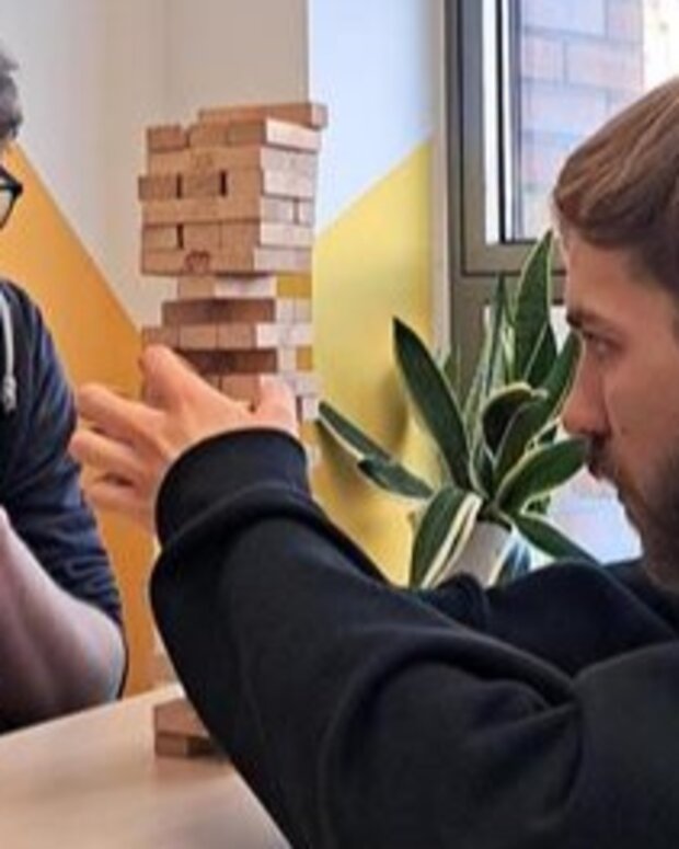 Zwei Schüler konzentrieren sich auf einen Turm aus Holzklötzen bei einem Geschicklichkeitsspiel.