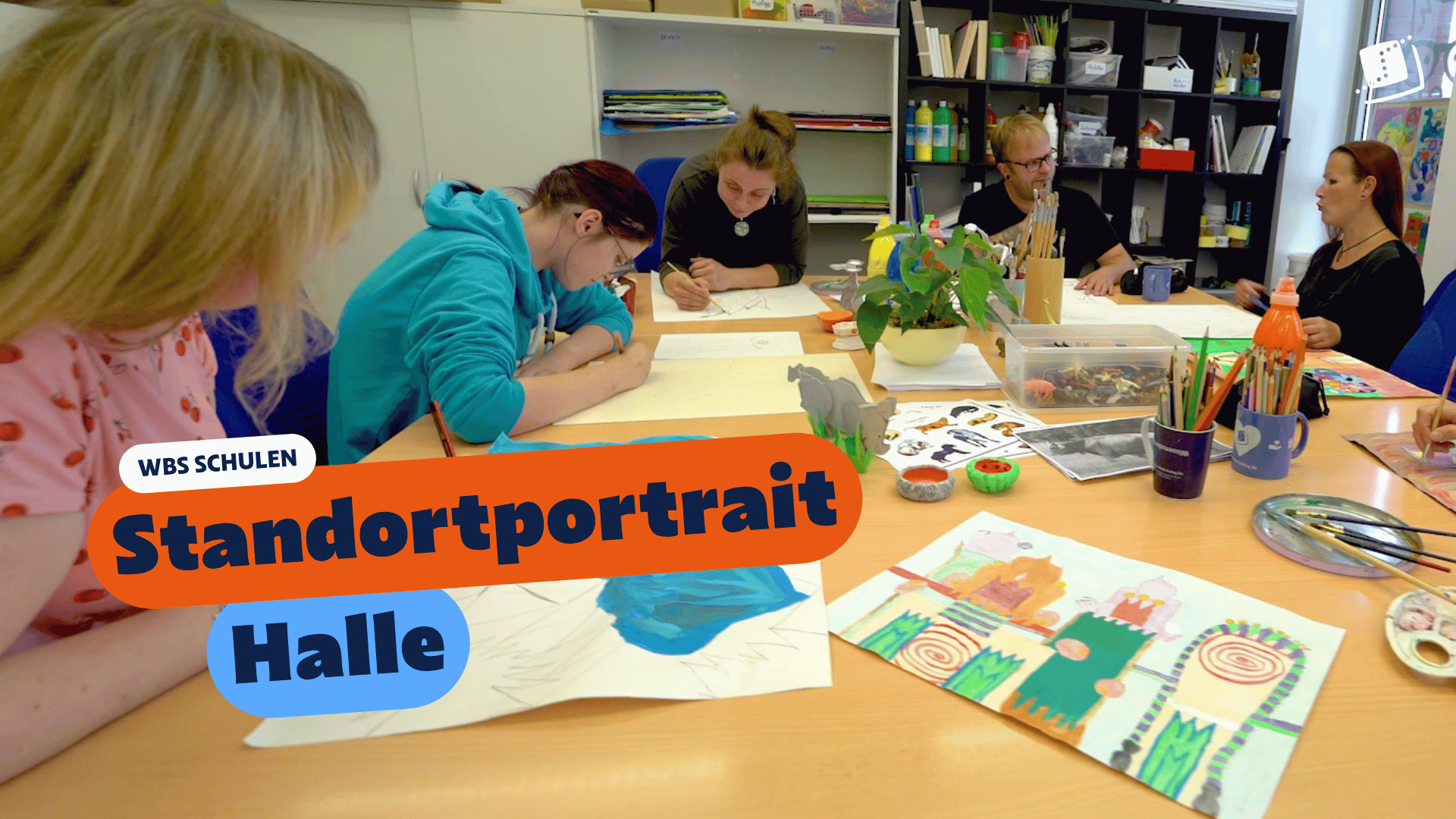 Zwei Personen sitzen an einem Tisch in einem Unterrichtsraum und betrachten gemeinsam ein anatomisches Handmodell. Eingeblendeter Text: „WBS SCHULEN – Standortportrait Plauen“.